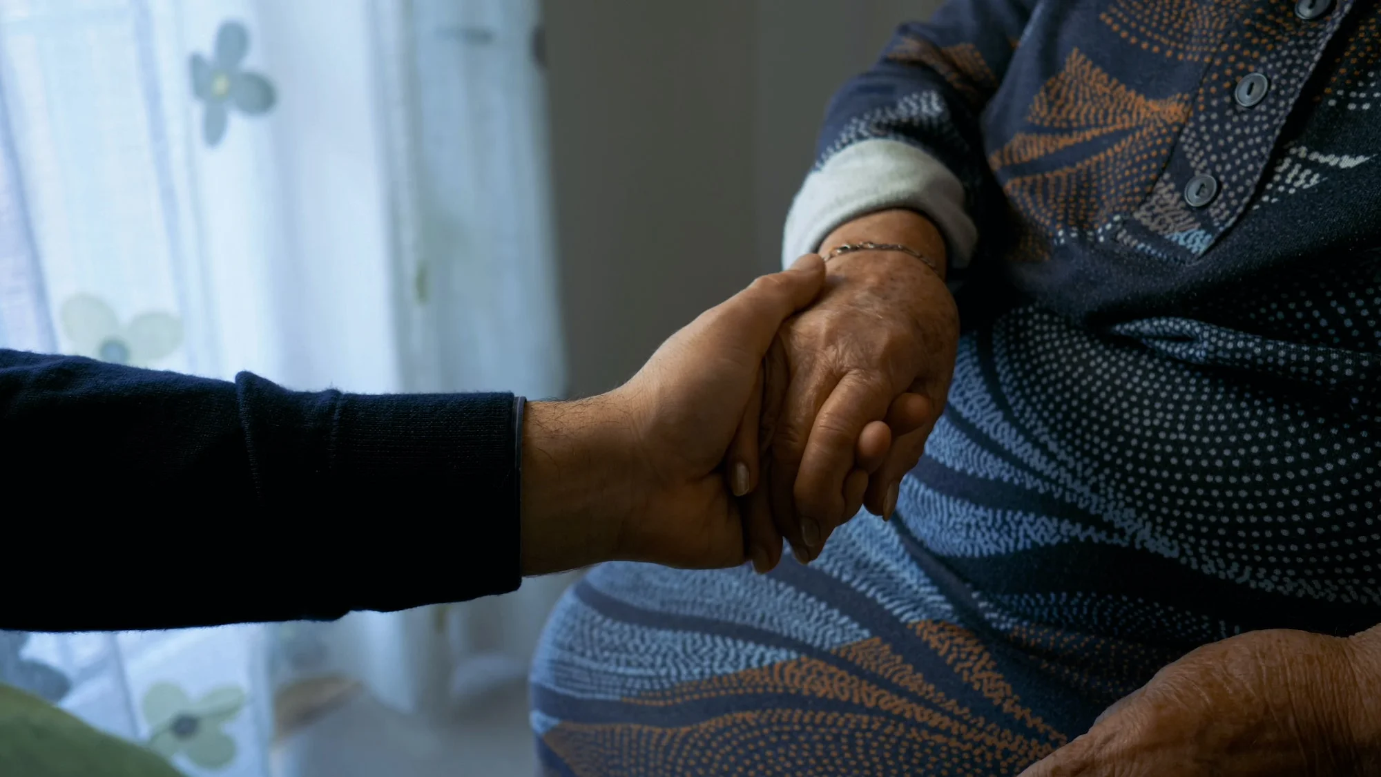 Young hand caressing the hand of an elderly woman.